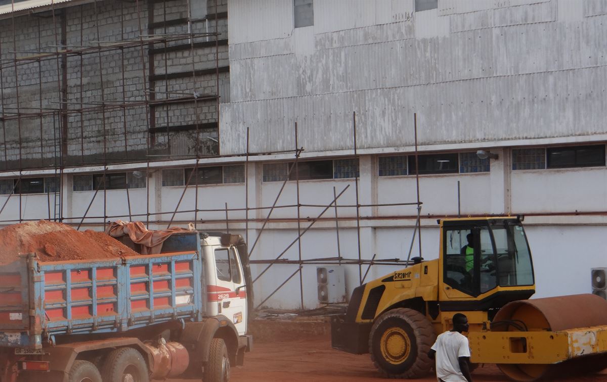 Tipper truck and roller working beside an industrial building